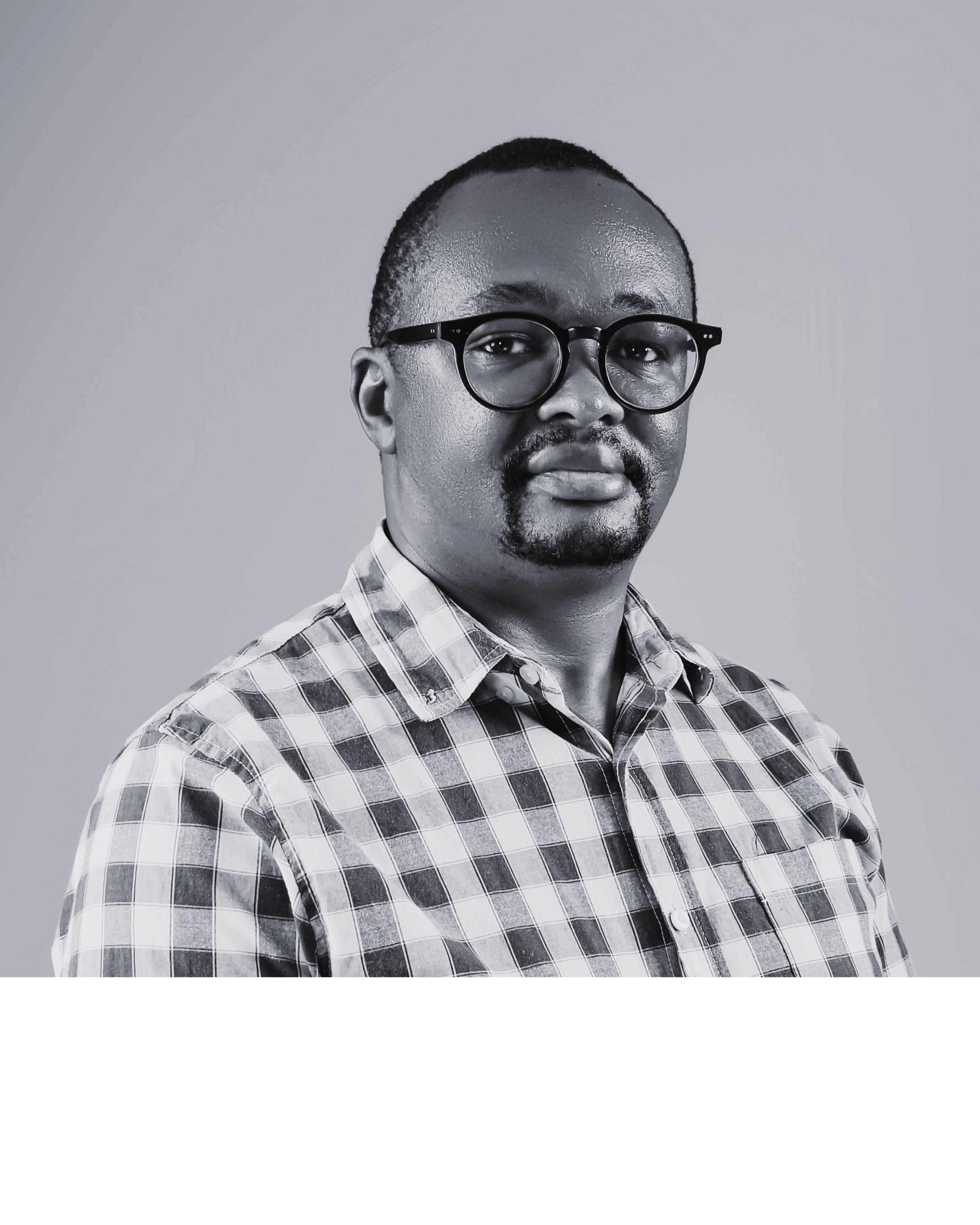 Portrait of Dr Job Mwaura wearing glasses and a checked shirt